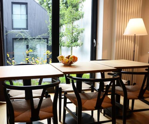 - deux tables avec des chaises et un bol de fruits dans l'établissement B&B A Côté du Cinquantenaire, à Bruxelles