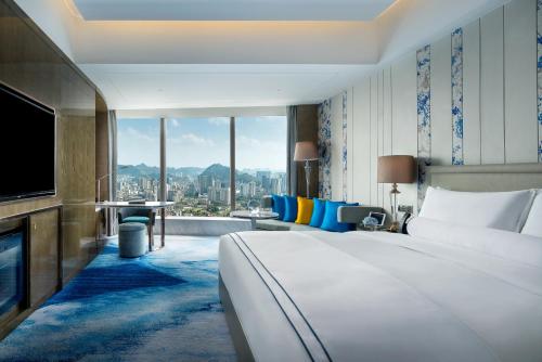 a hotel room with a large bed and a television at Sofitel Guiyang Hunter in Guiyang