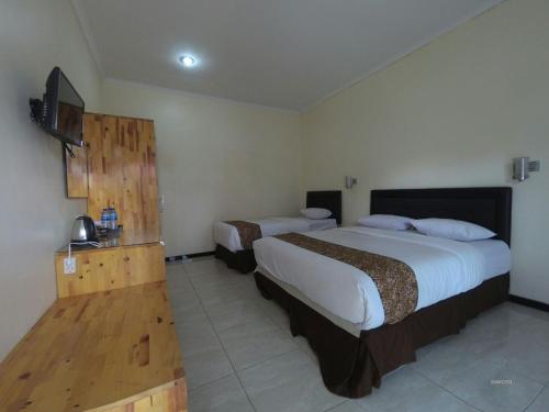 a hotel room with two beds and a television at Dieng Kledung Pass Hotel & Restaurant in Wonosobo