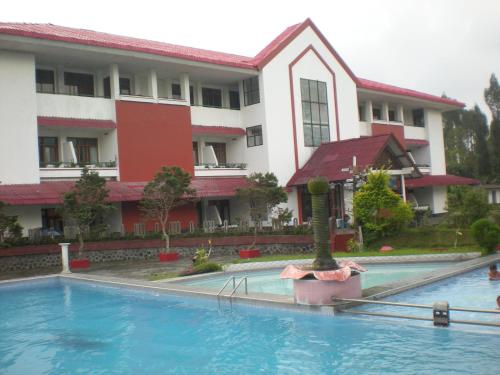 a hotel with a swimming pool in front of a building at Dieng Kledung Pass Hotel & Restaurant in Wonosobo