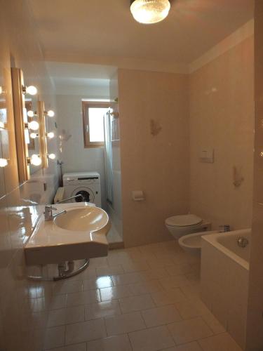 a bathroom with a sink and a toilet and a tub at Appartamenti Osti Sansoni Mariarosa in Andalo