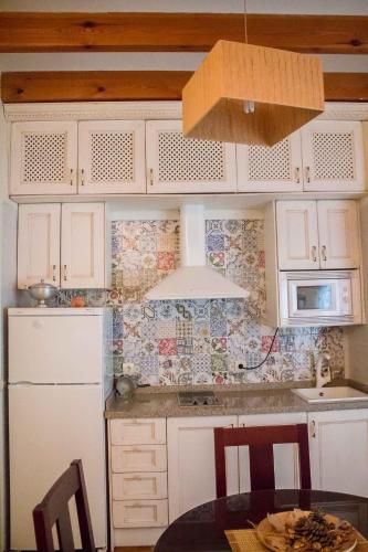 a kitchen with white cabinets and a table and a microwave at La Casa de Las Titas in Vélez-Málaga