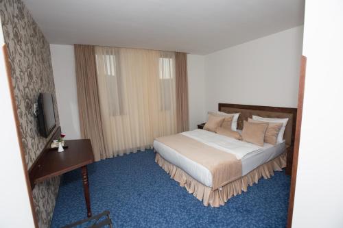 a bedroom with a bed and a desk and a television at Faria Boutique Hotel in Tsaghkadzor