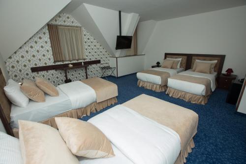 a hotel room with three beds and a television at Faria Boutique Hotel in Tsaghkadzor