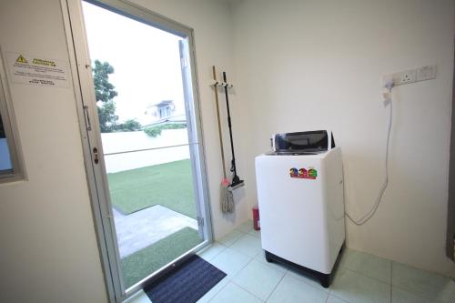 a small refrigerator in a room with a sliding glass door at Come Inn Homestay 1379 in Miri