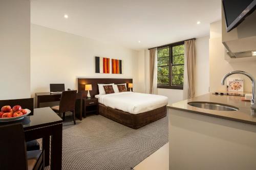 a hotel room with a bed and a desk and a kitchen at Quest Canberra in Canberra