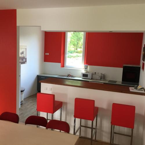 a kitchen with red cabinets and red bar stools at Domaine de Bel Air in Cérans-Foulletourte