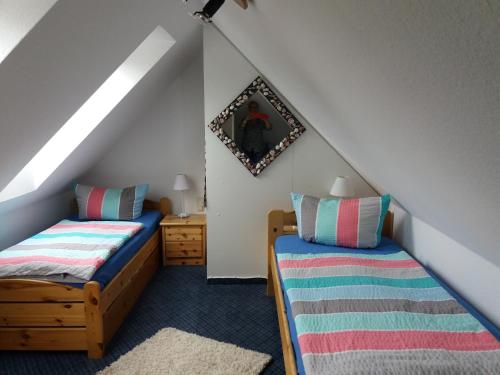 ヴィリンゲンにあるHaus Elsholz Willingenのベッド2台と窓が備わる屋根裏部屋です。