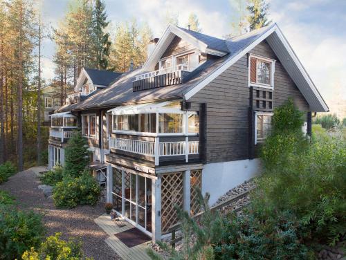 a house with a wrap around porch and a deck at Vuokatin Aateli Kreivi in Vuokatti