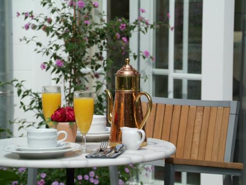 a table with a tea kettle and two glasses of orange juice at The Black Swan Hotel in Bruges