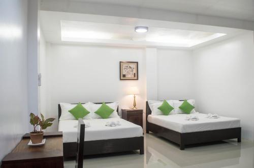 Cette chambre comprend 2 lits avec des oreillers verts. dans l'établissement Abeth's Haven, à Puerto Princesa