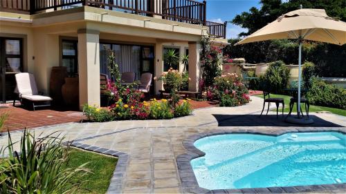 a house with a swimming pool and an umbrella at Panorama Guest House in Port Alfred