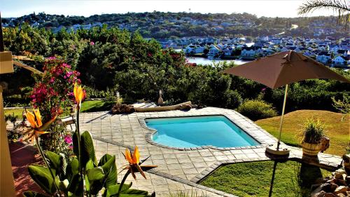 a swimming pool with an umbrella and a view of a resort at Panorama Guest House in Port Alfred