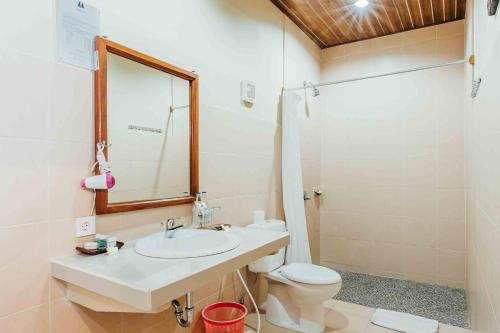 a bathroom with a sink and a toilet and a mirror at Kuta Puri Bungalows, Villas and Resort in Kuta