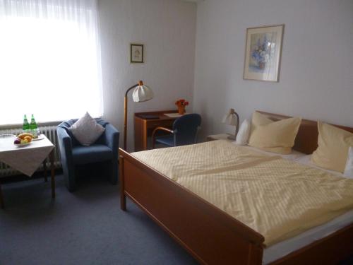 a bedroom with a bed and a chair and a table at Pension Haus Wernemann in Bad Rothenfelde