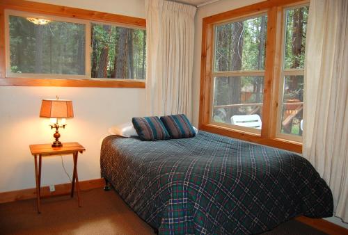 a bedroom with a bed and two windows and a lamp at 78 Ox Yoke in Wawona