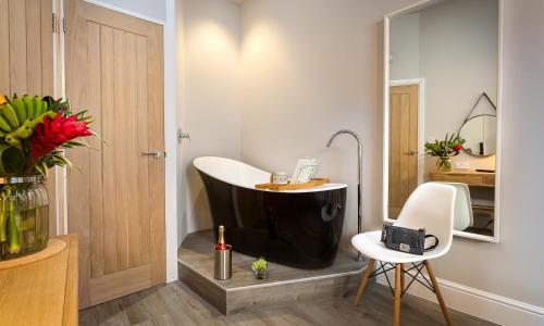 a bathroom with a black tub and a white chair at No 1, Midland Bank Chambers in Ambleside