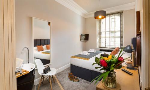 Un dormitorio con una cama y un escritorio con un jarrón de flores en No 1, Midland Bank Chambers, en Ambleside