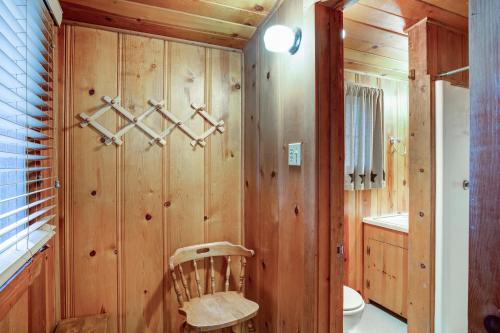 a bathroom with wooden walls and a toilet and a chair at 53 Creekside Cabin in Wawona