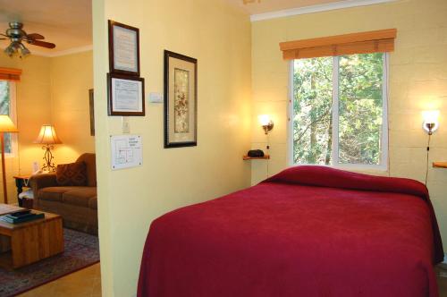 a bedroom with a red bed and a living room at 65 Sparrows Nest in Wawona