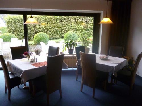 una sala da pranzo con tavoli, sedie e una grande finestra di Pension Haus Wernemann a Bad Rothenfelde