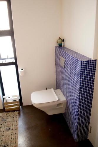 a bathroom with a toilet with a blue tiled wall at The Rez Guesthouse in Walvis Bay