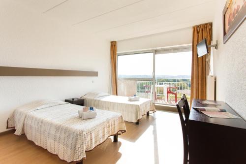 a hotel room with two beds and a large window at Village Vacances Le Kangourou (by Popinns) in Fréjus