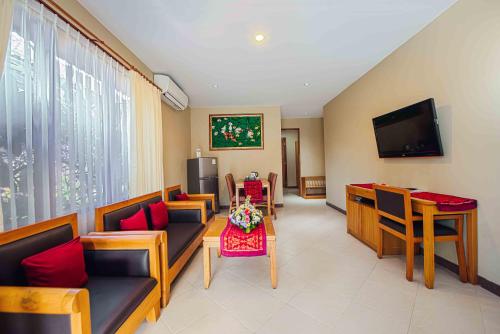 a living room with couches and a tv and a table at Kuta Puri Bungalows, Villas and Resort in Kuta