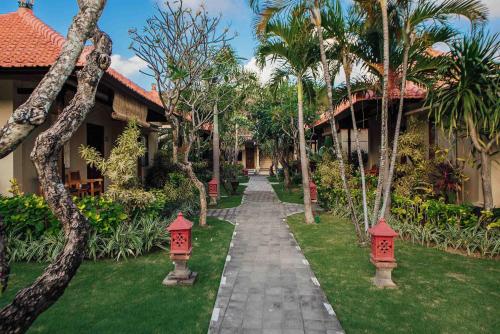 a walkway in front of a house with palm trees at Kuta Puri Bungalows, Villas and Resort in Kuta