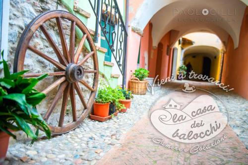a wooden wheel sitting next to a building with plants at La Casa dei Balocchi B&B in Toirano