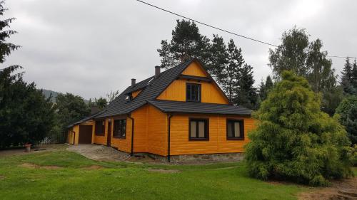a small yellow house with a black roof at Willa Stróża in Myślenice