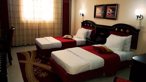 a hotel room with two beds and a phone at Urban Rose Hotel & Apartments in Dar es Salaam