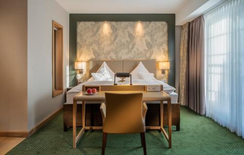 a hotel room with a desk and a bed at Romantik Hotel Jagdhaus Eiden am See in Bad Zwischenahn