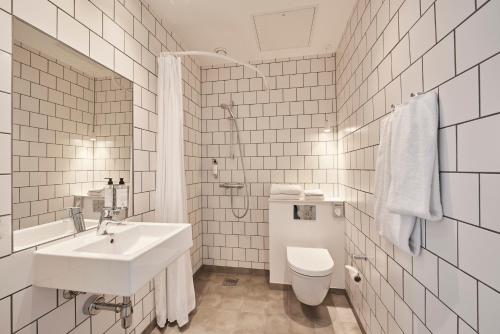 a bathroom with a sink, toilet, and bathtub at Zleep Hotel Copenhagen City in Copenhagen