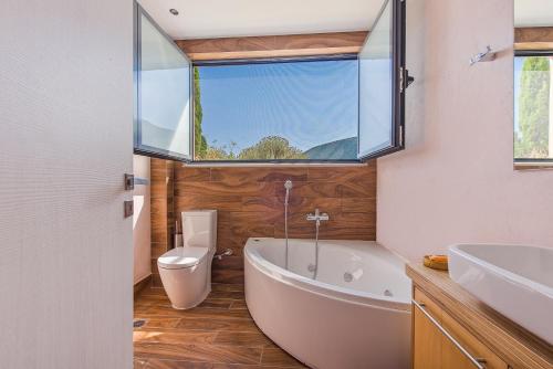 a bathroom with a tub and a toilet and a window at The Dynasty Villas in Sivota