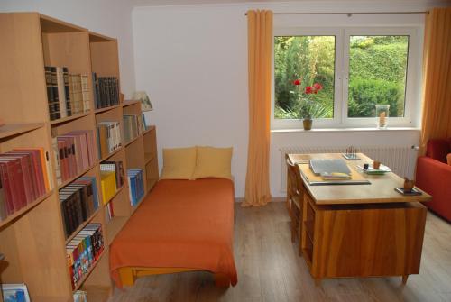 Zimmer mit einer Bibliothek mit einem Schreibtisch und einem Fenster in der Unterkunft Wohlfühlapartment in Minden in Minden