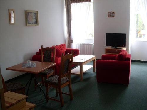 sala de estar con sillas rojas, mesa y TV en Hotel Krokus, en Kamienna Góra