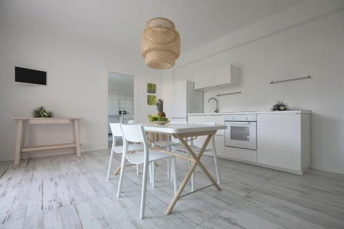 a white kitchen with a table and white chairs at Camarò Favignana in Favignana