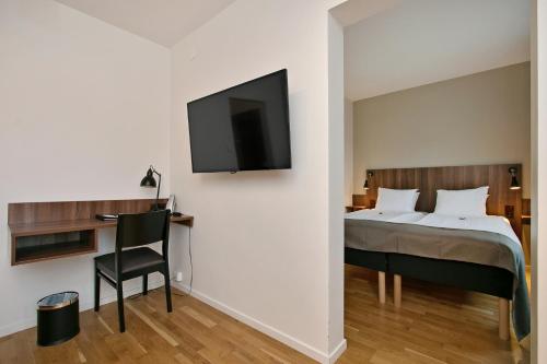 a bedroom with a bed and a tv on a wall at First Hotel Brommaplan in Stockholm
