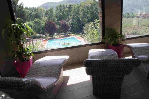 Habitación con vistas a la piscina, sillas y ventana. en Hostal Els Roures, en Camprodon