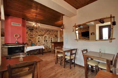 una sala da pranzo con tavoli, sedie e camino di Thea Valtessinikou a Valtessiniko