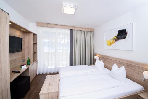 a bedroom with two white beds and a television at Terrassenhotel Reichmann in Sankt Kanzian