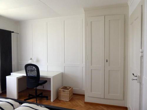 a white bedroom with a desk and a chair at Chalet in Bern in Bern