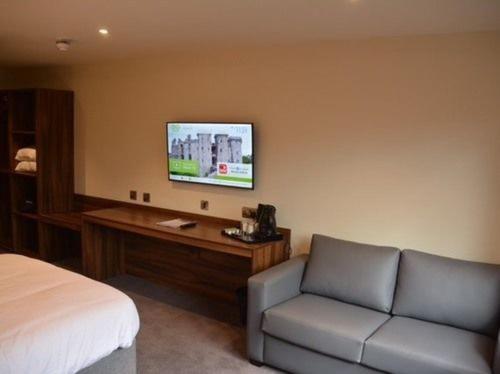 1 dormitorio con cama, sofá y TV en Raglan Lodge, en Monmouth