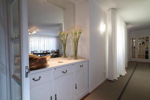 ein weißes Badezimmer mit einer Vase mit Blumen auf einer Ablage in der Unterkunft ARTS In Penthouse Apartments Til Sol in Funchal