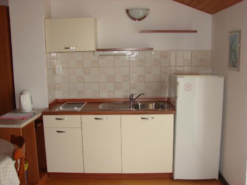 a kitchen with a sink and a white refrigerator at Apartments & Rooms Luka in Starigrad