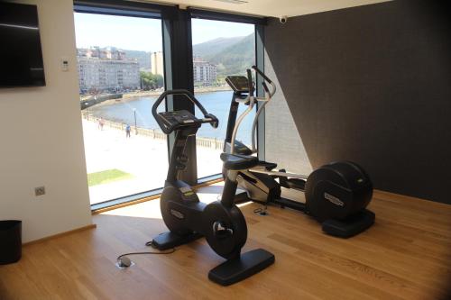 un gimnasio con dos máquinas de correr y una gran ventana en Hotel U Viveiro en Viveiro