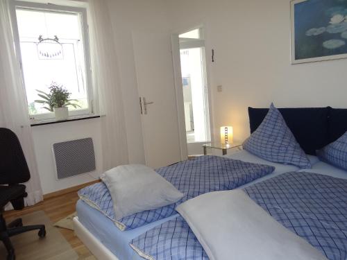 1 dormitorio con 2 camas con almohadas azules y ventana en Ferienwohnung Großwald, en Saarbrücken