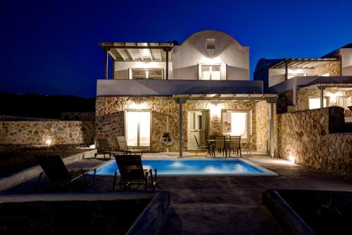 a villa with a swimming pool at night at Desiterra Resort & Spa in Fira
