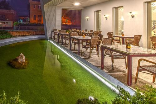 a patio with tables and chairs and a green lawn at Anna Hotel in Budapest